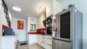 A modern kitchen with a stainless steel refrigerator, a built-in oven, and a window with a view. - Modern Holiday Home by Beach in Calahonda (Mijas)