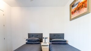 A room with two single beds, a bedside table with a lamp, and a painting on the wall. - Modern Holiday Home by Beach in Calahonda (Mijas)