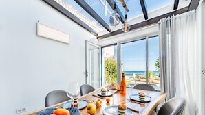 A dining area with a wooden table, chairs, a fruit bowl, wine glasses, and a bottle of wine. - Modern Holiday Home by Beach in Calahonda (Mijas)