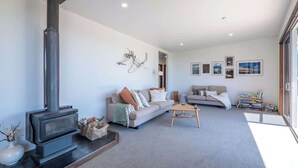 A modern living room with a fireplace, two sofas, a coffee table, and a bookshelf. - Pohara's Beachside Bliss (Pōhara)