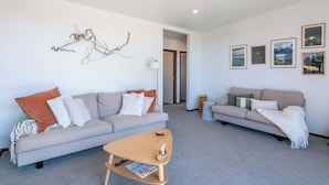 A modern living room with two sofas, a coffee table, and wall art. - Pohara's Beachside Bliss (Pōhara)