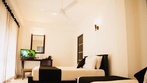 A hotel room with two beds, a desk with a computer, a television, and a ceiling fan. - 49 Ella (Ella)