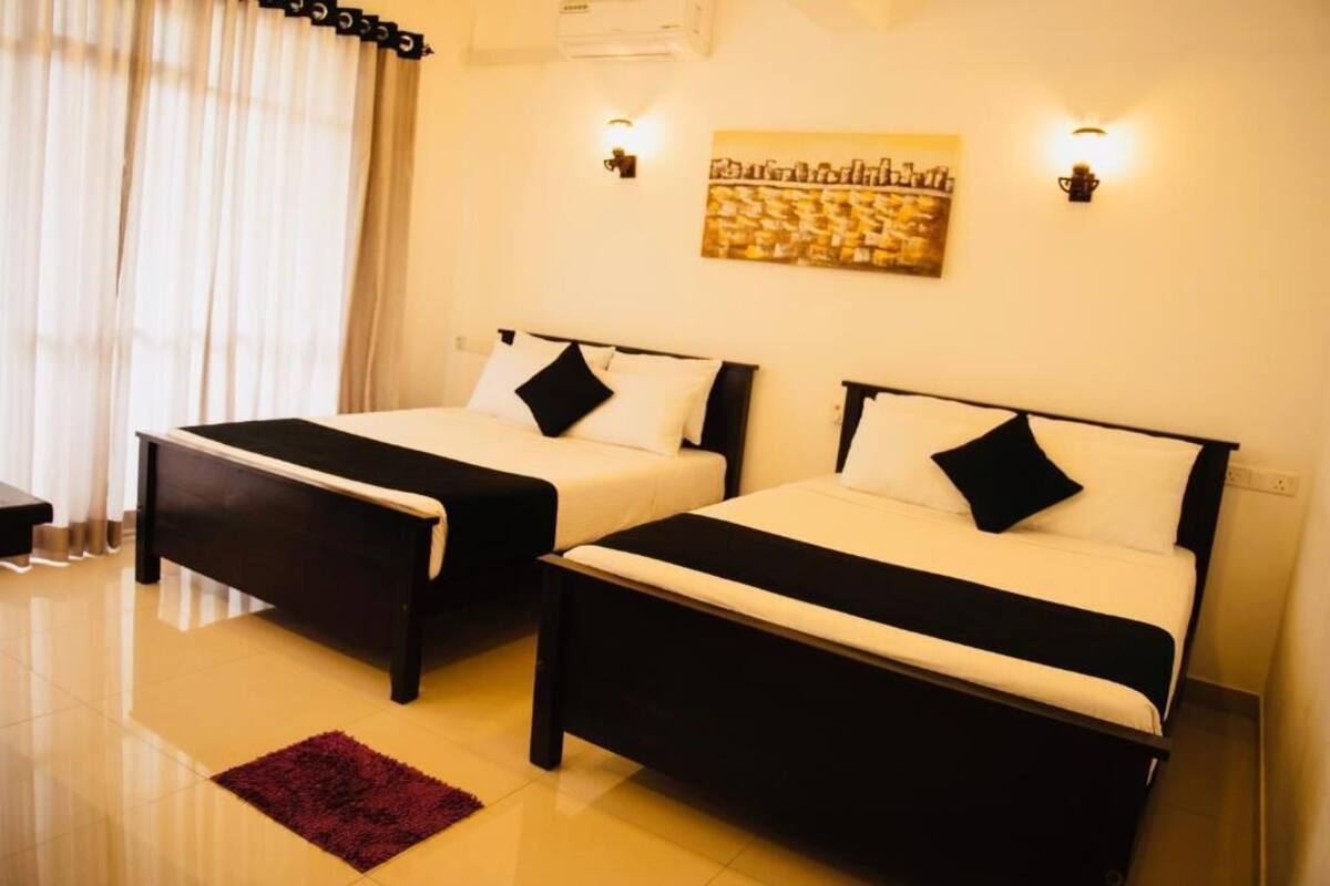 A hotel room with two beds, a red rug, and a painting on the wall.