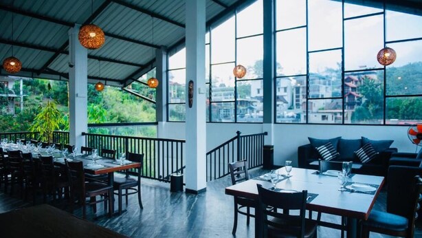 A restaurant with tables and chairs, large windows, and hanging light fixtures. - 49 Ella (Ella)