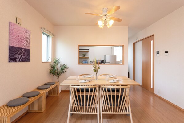 A dining area with a wooden table, four chairs, a ceiling fan, and a bench with cushions.