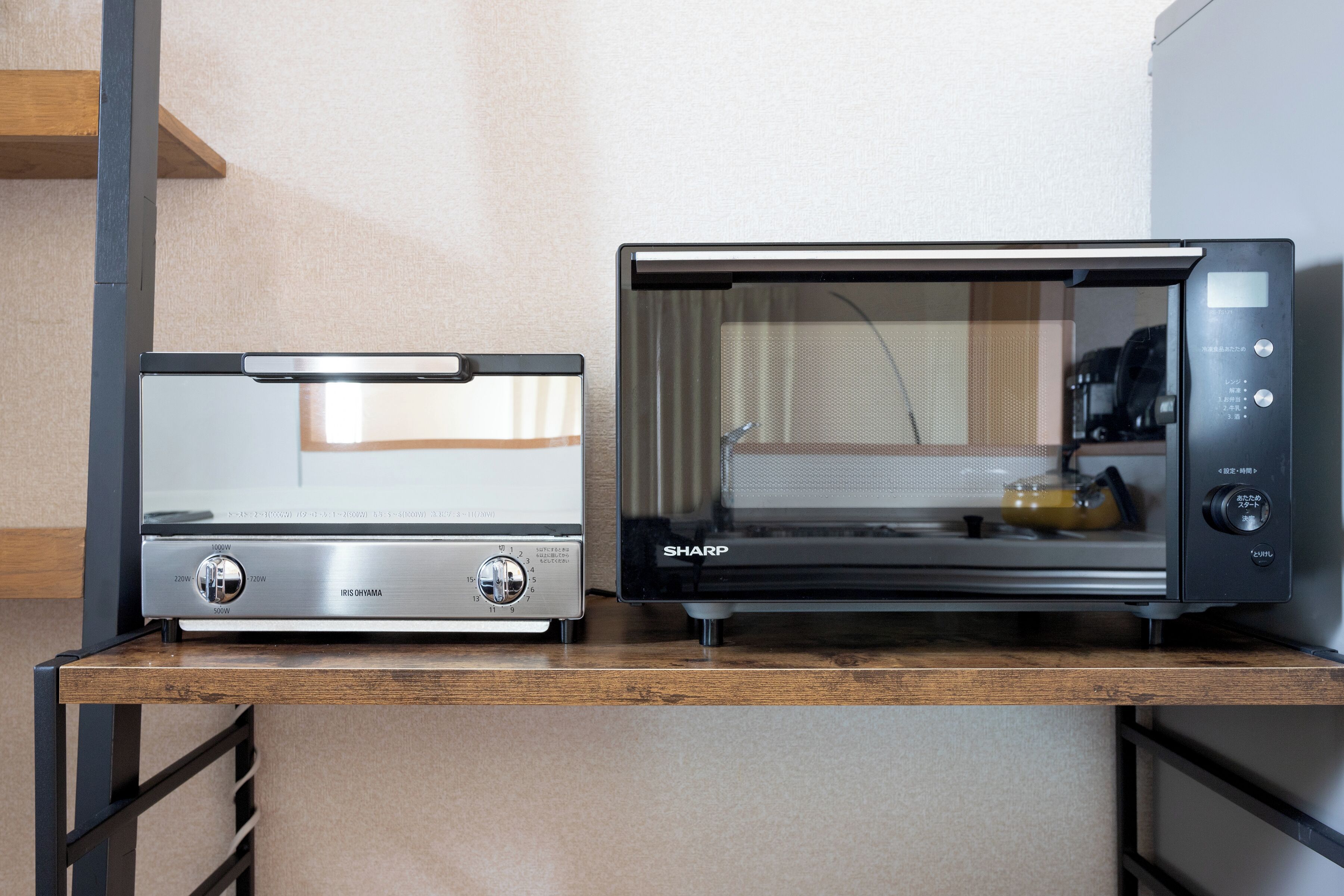 Two kitchen appliances, a toaster and a microwave, on a wooden countertop.