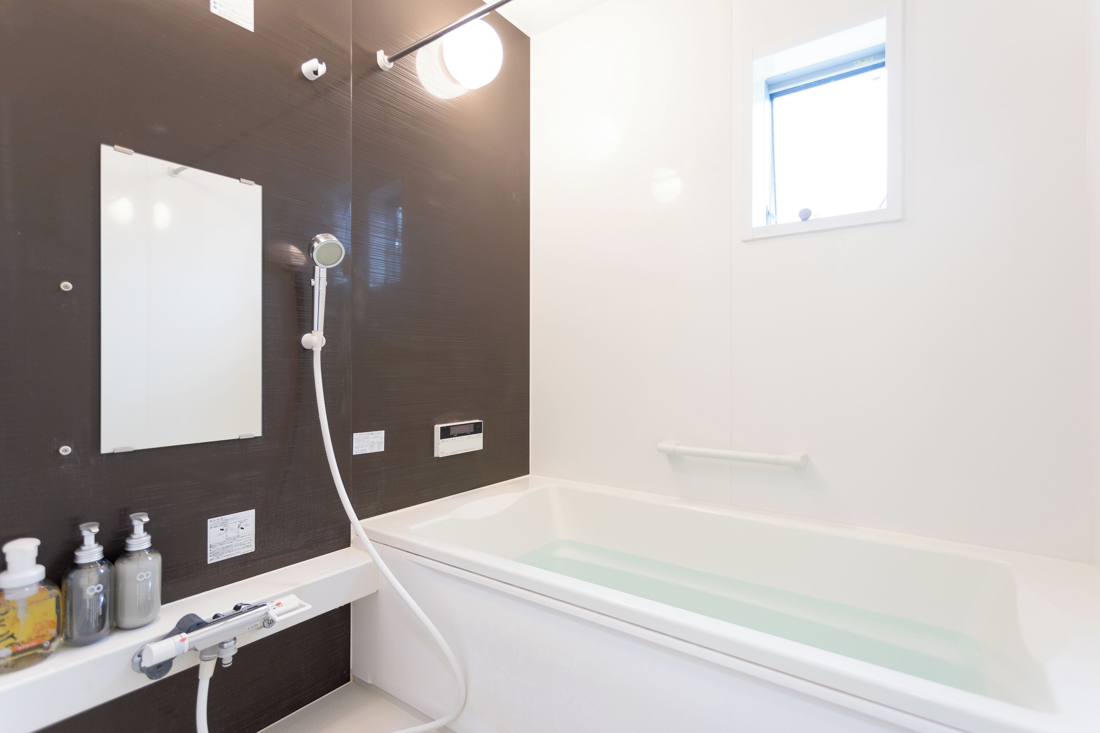 A modern bathroom with a bathtub, a mirror, and a window.