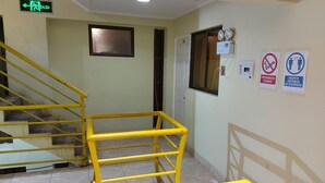Eine Treppe mit gelben Handläufen, einem grünen Hinweisschild für den Ausgang und Sicherheitsschildern an der Wand.