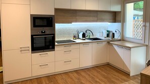 Una cucina moderna con mobili bianchi, forno, microonde e lavandino.