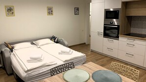 Una camera da letto con un letto, comodini, una scrivania con una sedia, angolo cottura con forno a microonde e televisore.