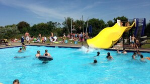 A swimming pool with a yellow slide and people swimming and playing. - Holiday Home Near Petten Beach With Pool (Petten)