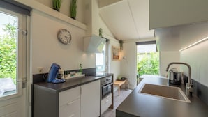 A modern kitchen with a built-in oven, a coffee machine, and a sink. - Holiday Home Near Petten Beach With Pool (Petten)