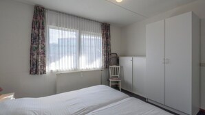Ein Schlafzimmer mit Bett, Stuhl, Kleiderschrank und Heizkörper.