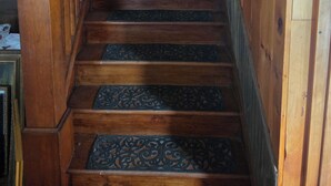 Una escalera de madera con barandilla y balaustradas metálicas decorativas.