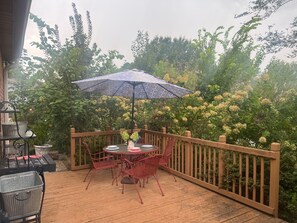 A wooden deck with a table and chairs, surrounded by a wooden fence and lush greenery. - Clarksville's Château Retreat (Clarksville)