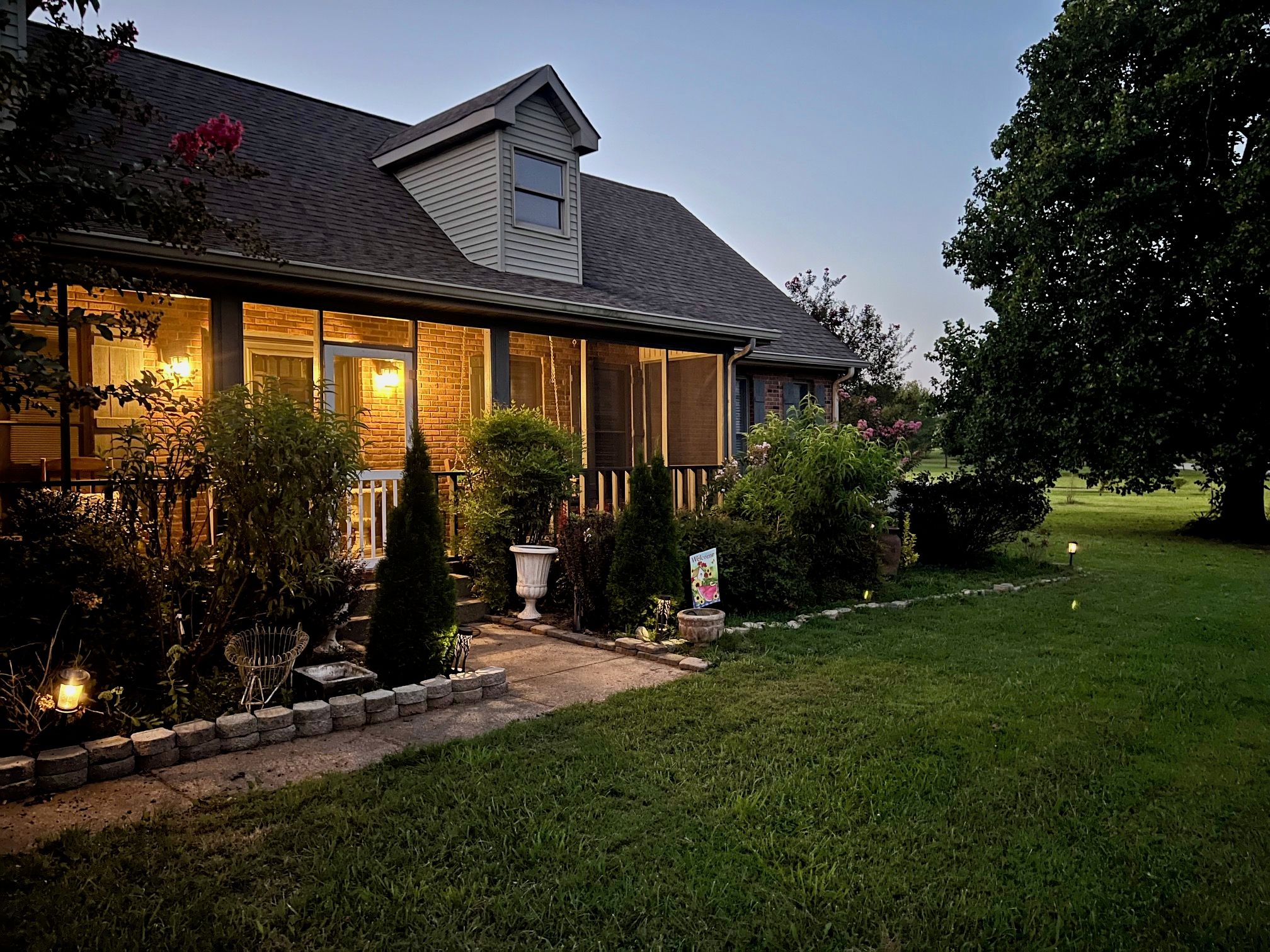 A two-story house with a covered porch, a brick exterior, and a well-maintained lawn.