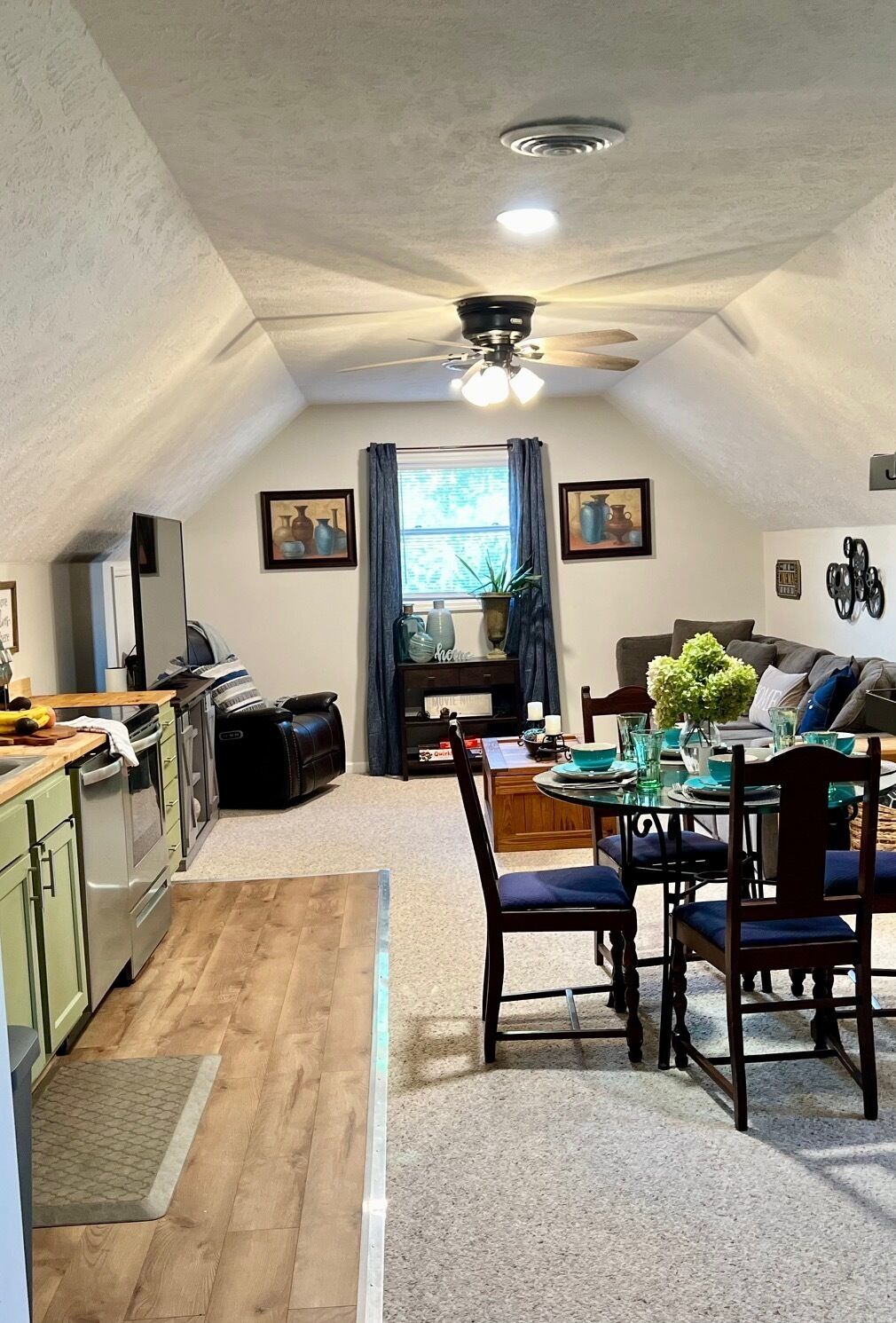 Un espacio de estar acogedor con comedor, cocina y ventilador de techo.