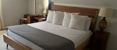 Une chambre à coucher avec un lit en bois, une table de chevet avec une lampe, une commode et un miroir.