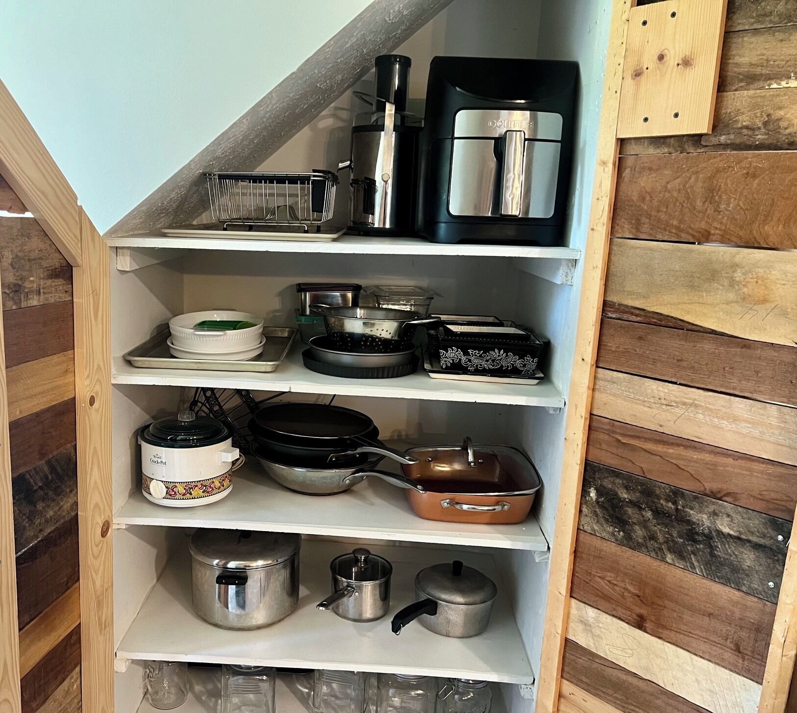 Una cocina con estantes de madera que contienen diferentes utensilios y electrodomésticos.