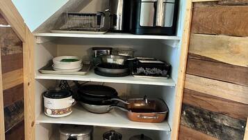 Una cocina con estantes de madera que contienen diferentes utensilios y electrodomésticos.