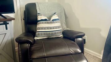 Un fauteuil inclinable en cuir noir avec un coussin décoratif à motifs.