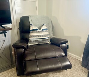 A black leather recliner with a patterned throw pillow. - Clarksville's Château Retreat (Clarksville)