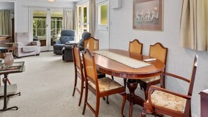 Un comedor con una mesa de madera redonda, seis sillas y una araña.