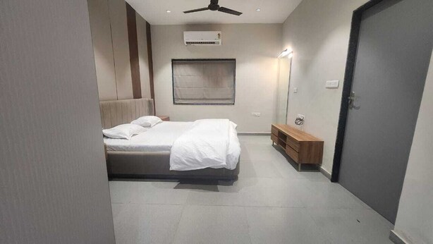 A bedroom with a bed, a bedside table, a mirror, a wardrobe, and an air conditioning unit. - Mahi river villas Beautyful riverside location pet friendly fully furnished vill (Bamangam)