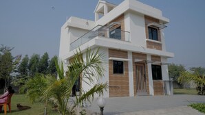 A modern two-story house with a balcony, a wooden door, and a clear sky. - Mahi river villas Beautyful riverside location pet friendly fully furnished vill (Bamangam)
