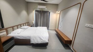 A hotel room with a bed, bedside table, and a mirror. - Mahi river villas Beautyful riverside location pet friendly fully furnished vill (Bamangam)