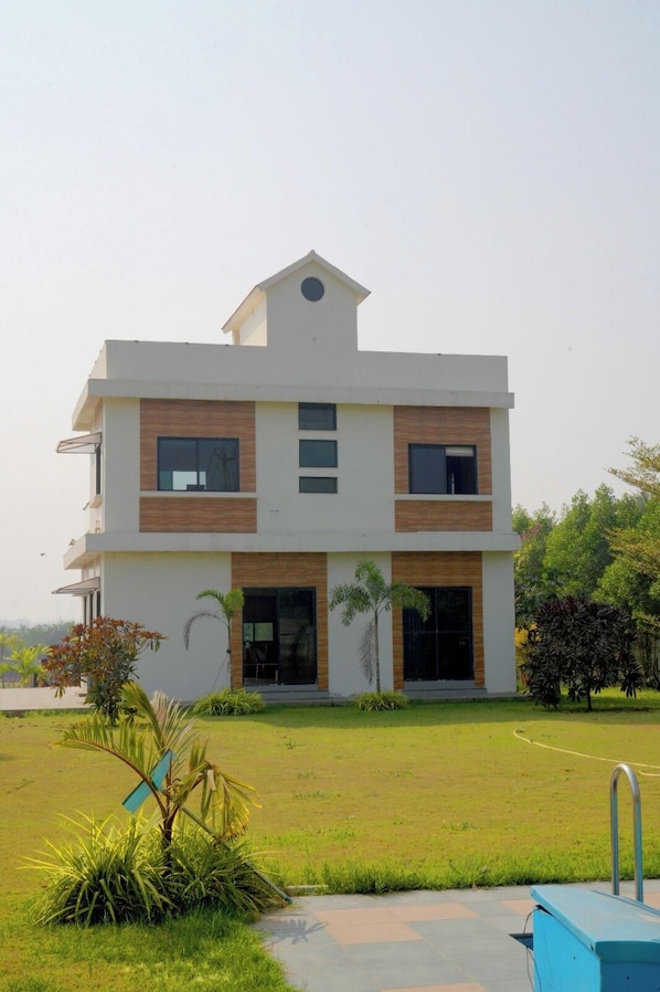 A modern two-story house with a flat roof, large windows, and a well-maintained lawn.