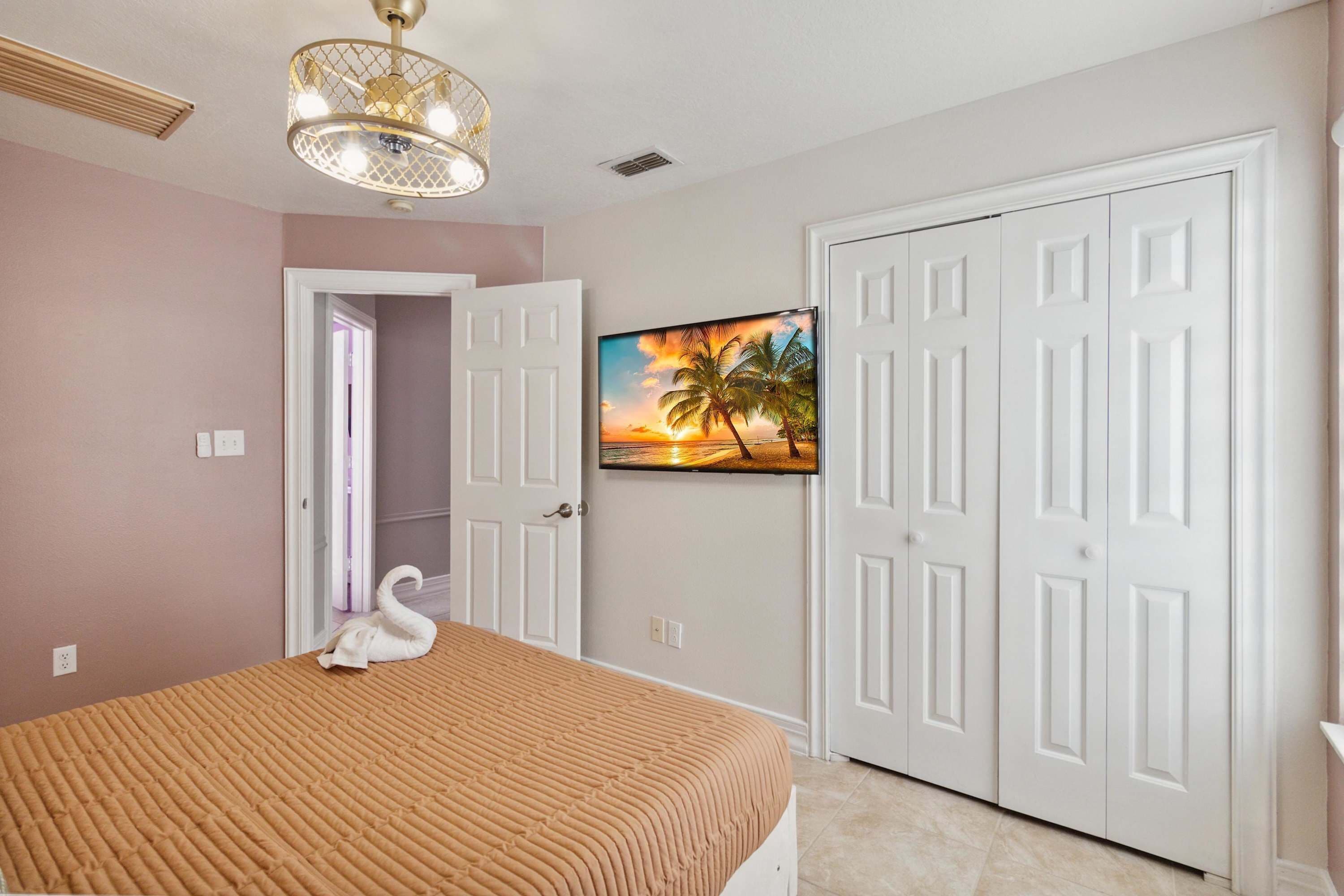A bedroom with a bed, a painting of a sunset, and white doors.