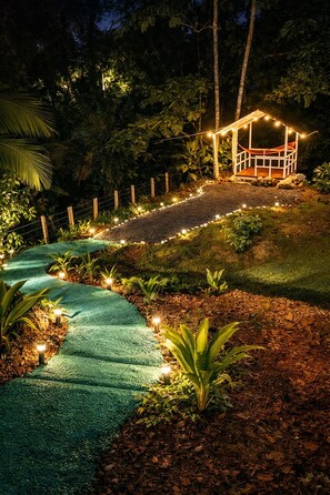 A garden pathway leading to a wooden gazebo with string lights. - Jungle Retreat with a Jacuzzi, River, and Near Arenal (La Fortuna)