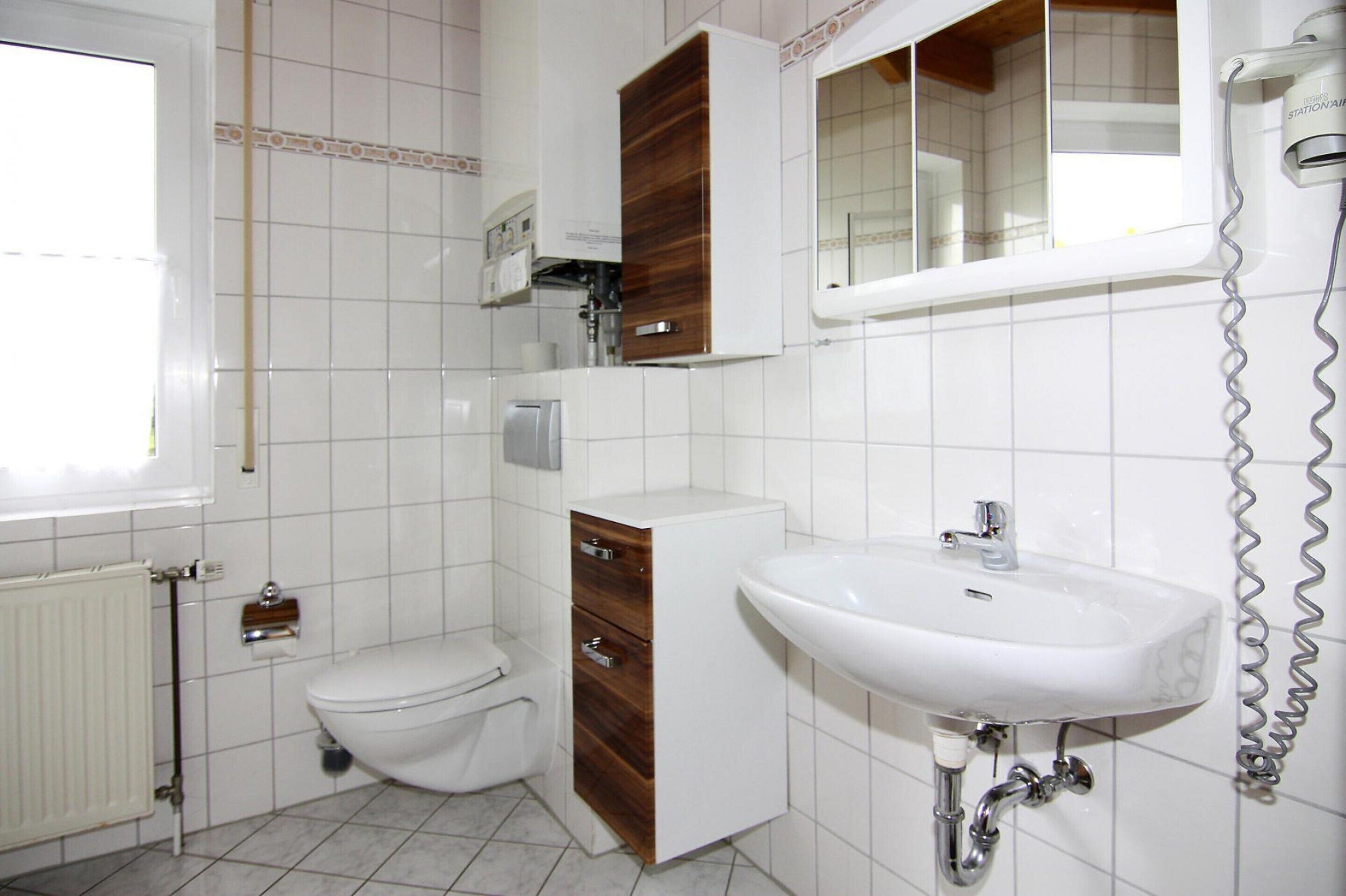 Un bagno con il water, un lavandino, uno specchio e un armadietto.