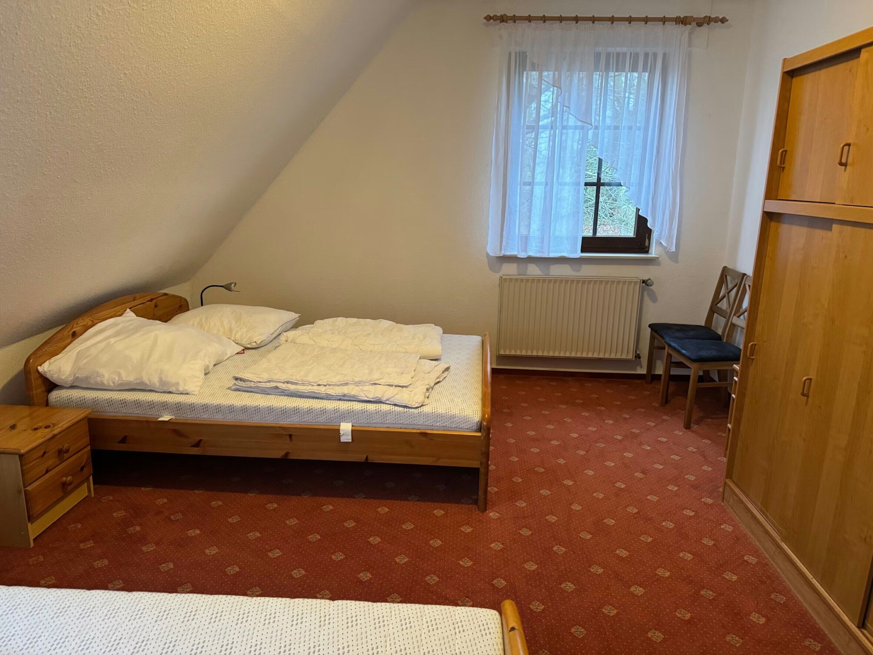 Una camera da letto con un letto, una sedia, un armadio e una finestra vista.