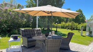 Eine Terrasse mit Korbmöbeln, einem Tisch und einem weißen Stuhl.