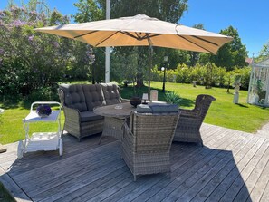 Eine Terrasse mit Korbmöbeln, einem Tisch und einem weißen Stuhl.