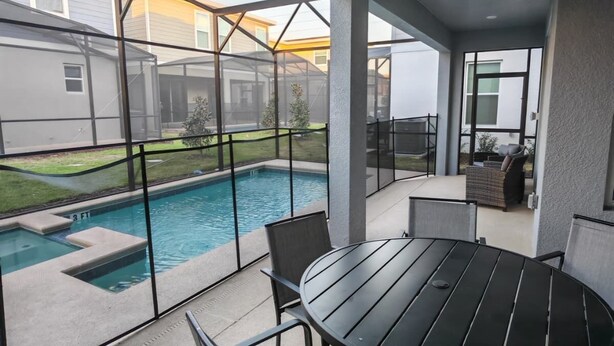 Un patio cubierto con piscina, mobiliario exterior y vistas al jardín trasero.