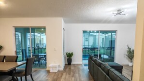 Amplia sala de estar con una mesa de comedor, sillas, un sofá y una planta en maceta.