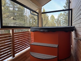 Un jacuzzi con plataforma de madera y vista a árboles.