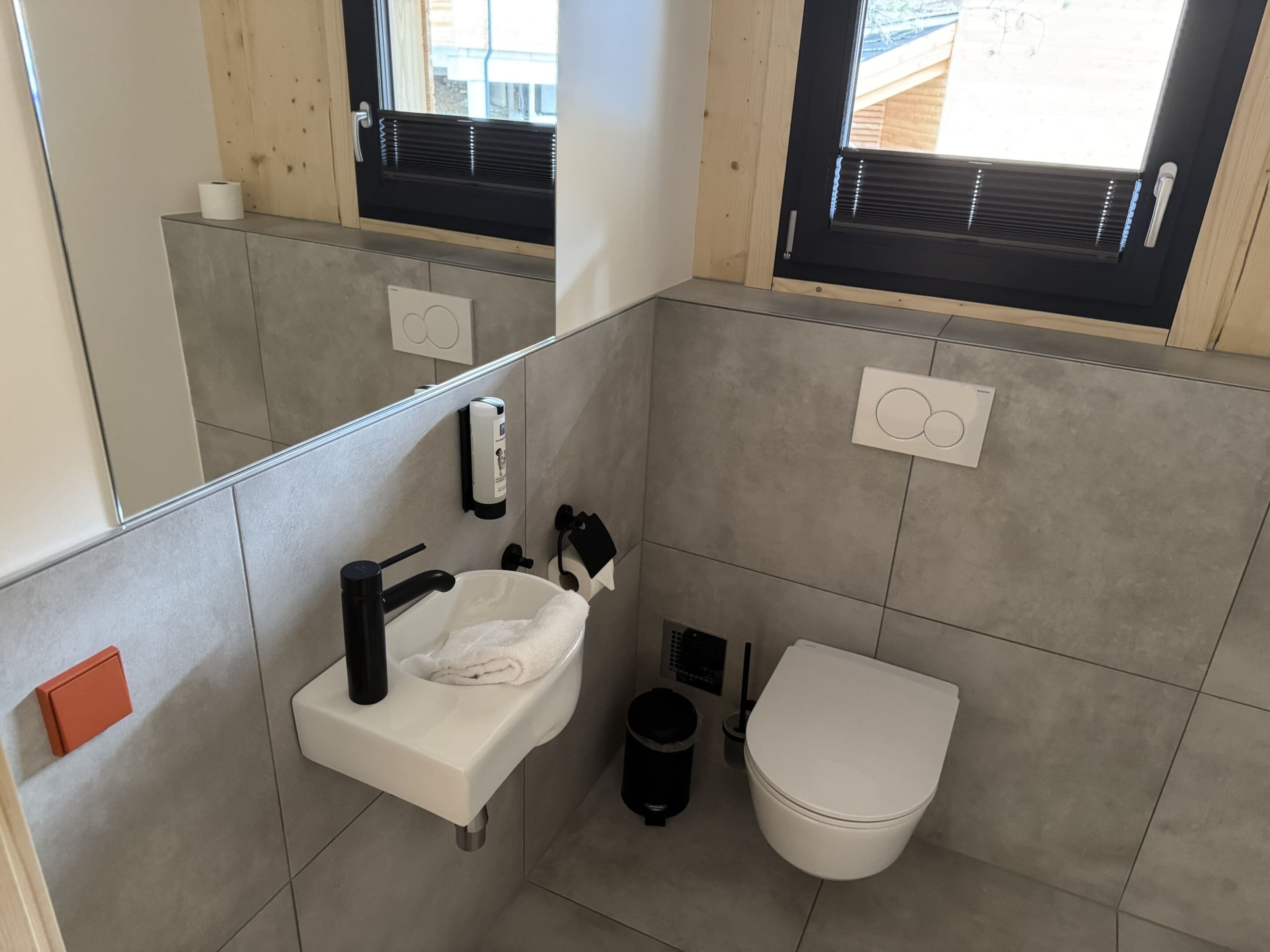 A modern bathroom with a sink, toilet, and a mirror.