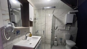 A bathroom with a sink, mirror, shower, toilet, and a towel rack. - new dome house (Sapanca)