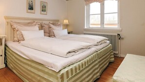 Un lit double bien fait, avec une couvre-lit à rayures, une table de chevet, une fenêtre donnant sur un beau paysage et un radiateur.