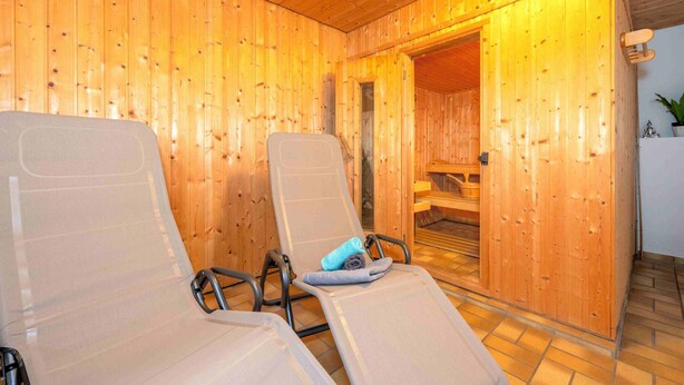 Un sauna con paredes de madera y dos sillones reclinables.