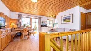 Un espacio de estar con piso de madera, que incluye una mesa de comedor, un sofá y una cocina al fondo.