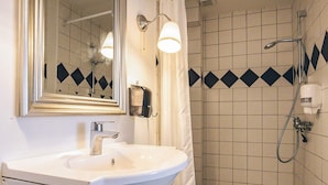 Ein Badezimmer mit Waschbecken, Spiegel, Dusche mit Duschbrause und Handtuchhalter.