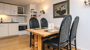 Ein Essbereich mit Holztisch, schwarzen Stühlen, einem weißen Schrank und einer Wandleuchte.