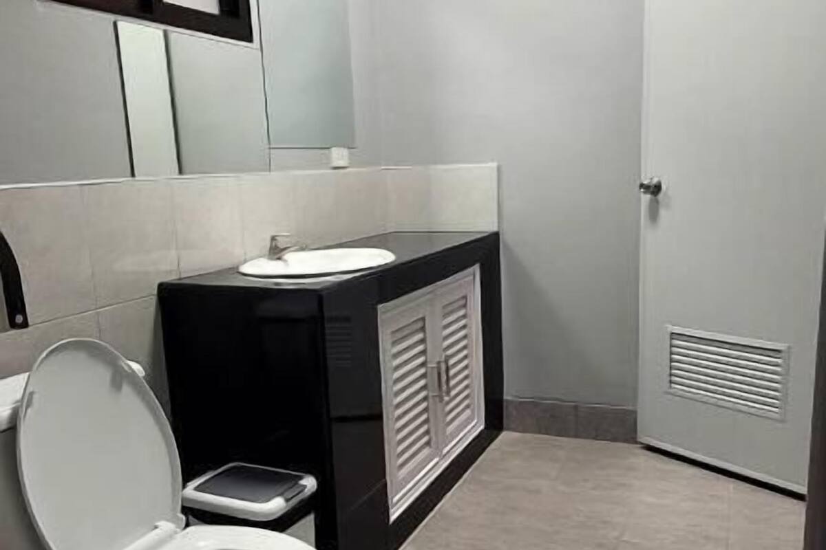 A bathroom with a toilet, a sink, a mirror, and a cabinet.