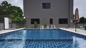 A swimming pool with a tiled edge, a building with a flat roof, and a few windows. - Dan Mai Homestay  (Ko Chang)