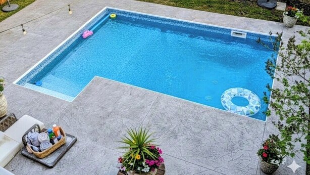 Une piscine rectangulaire avec un flotteur périphérique, entourée d’une clôture en bois, d’une pelouse et de plantes en pot.